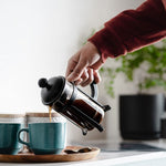 Pouring organic coffee from French press into mug