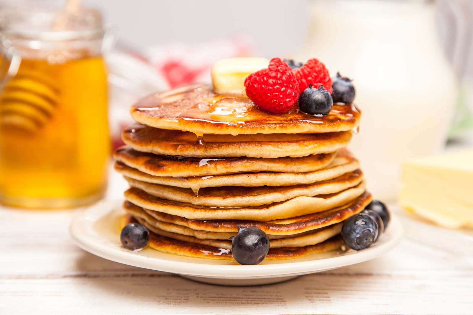 Stack of golden pancakes with maple syrup and blueberries, made with Yonder collagen